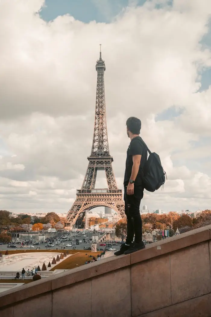 our-services-1 A tourist stands with a backpack admiring the Eiffel Tower in Paris during the day.