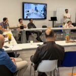 Salle de réunion avec des participants à une rencontre consultative de journalistes et professionnels des médias syriens en France, avec une participation à distance affichée sur un écran